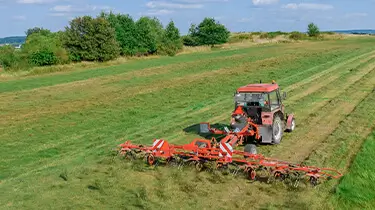 Tractor raking field of hay